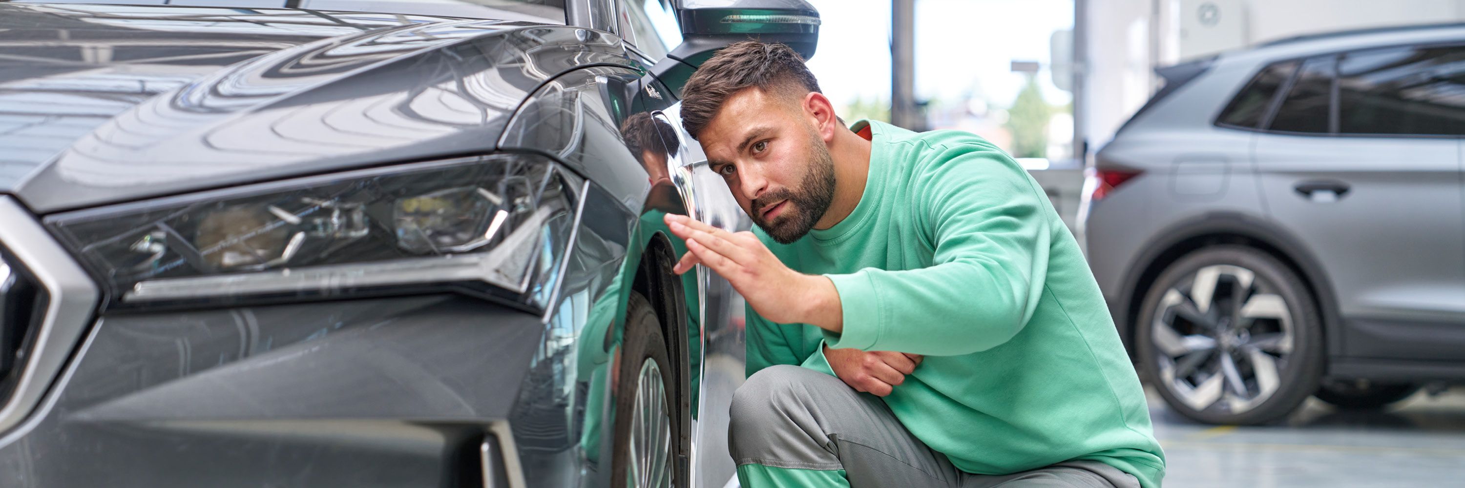 Ein Škoda Mechaniker kontrolliert den Lack bei einem grauen Škoda.