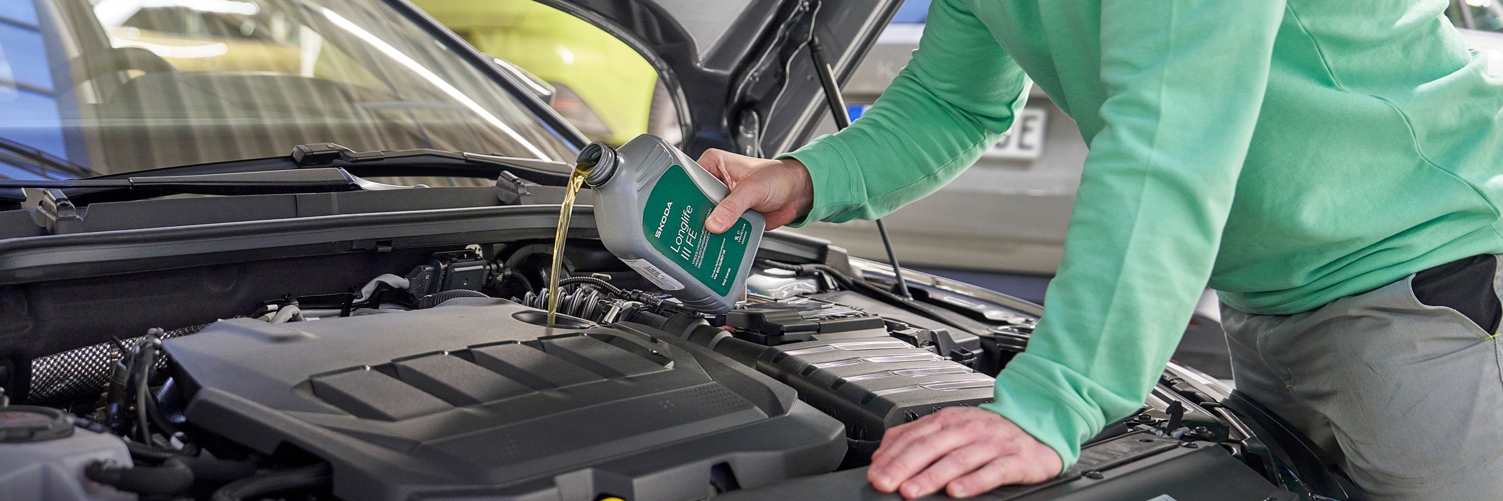 Ein Škoda Mechaniker beim Nachfüllen von Motoröl.
