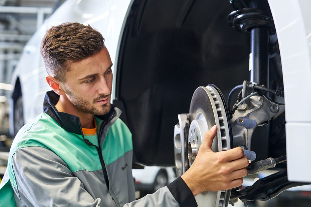 Ein Škoda Mechaniker beim Bremsenwechsel. 