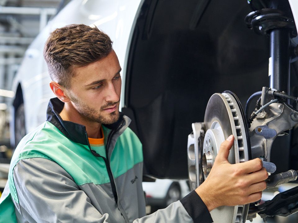 Ein Škoda Mechaniker beim Bremsenwechsel. 