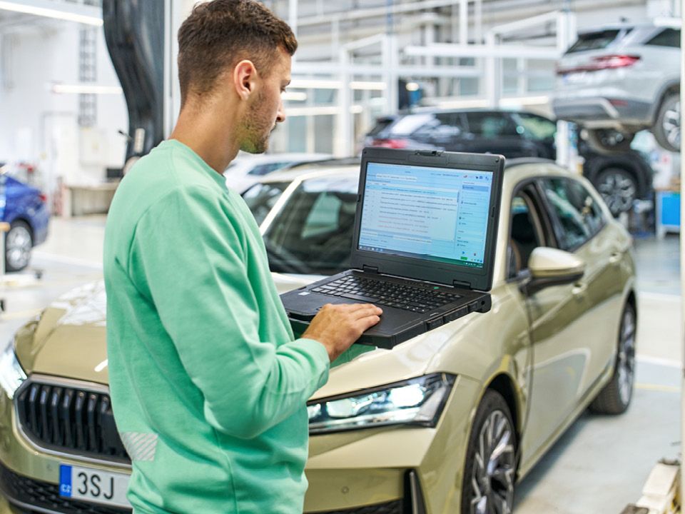 Ein Škoda Mechaniker überprüft Werte eines Škoda auf seinem Laptop.