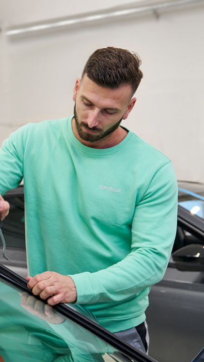 Ein Škoda Mechaniker repariert eine Windschutzscheibe.