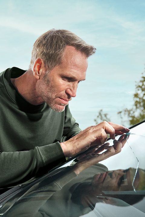 Ein Škoda Techniker kontrolliert einen Steinschlagschaden an einer Windschutzscheibe.