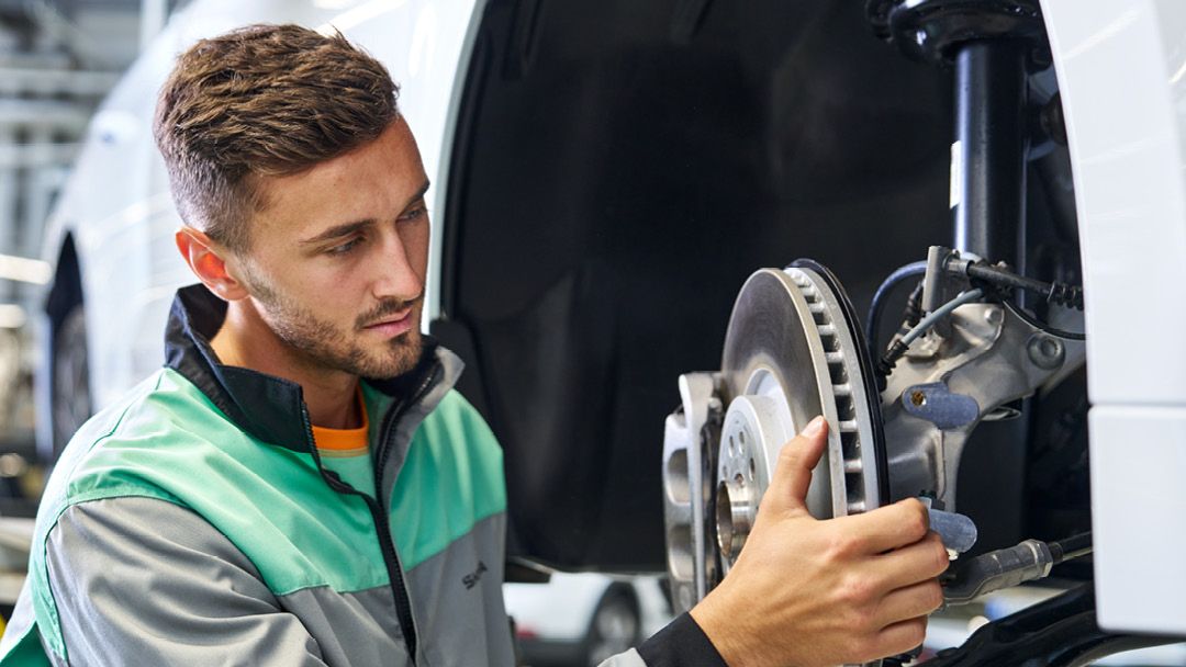 Ein Škoda Mechaniker beim Bremsenwechsel. 