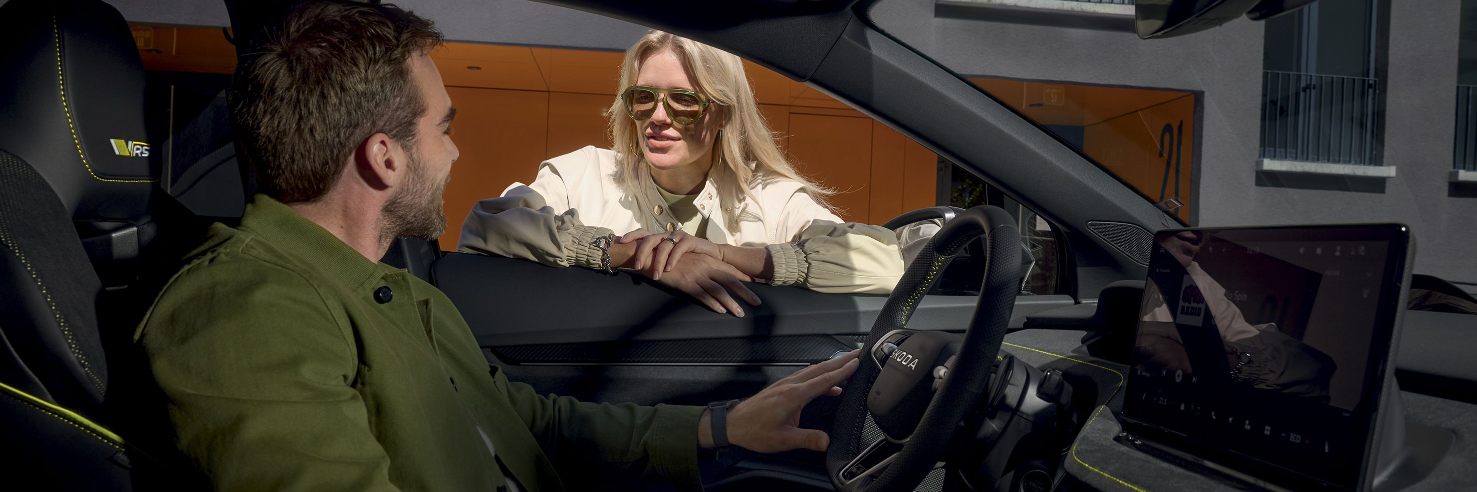 Eine Person sitzt in einem Auto und redet mit einer Person außerhalb des Autos