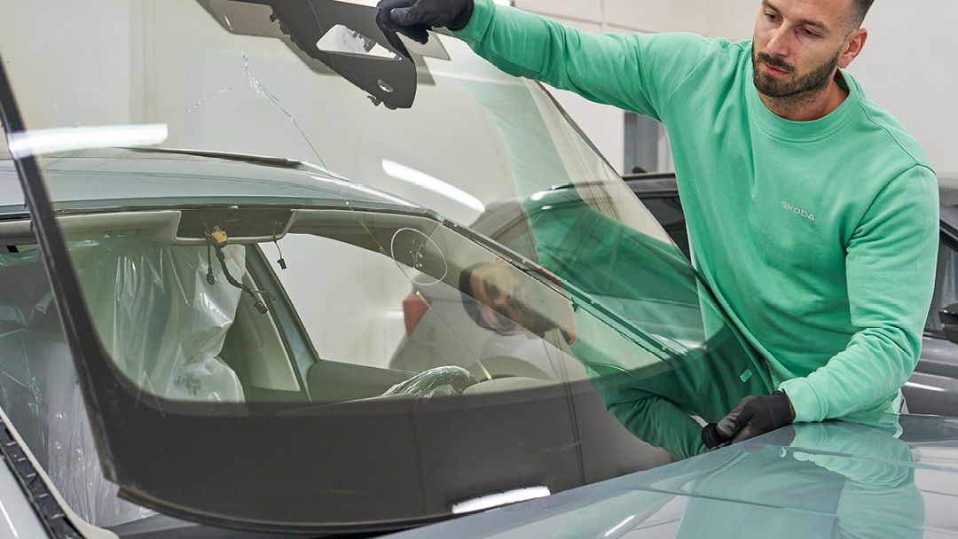 Ein Škoda Mechaniker tauscht eine Windschutzscheibe.