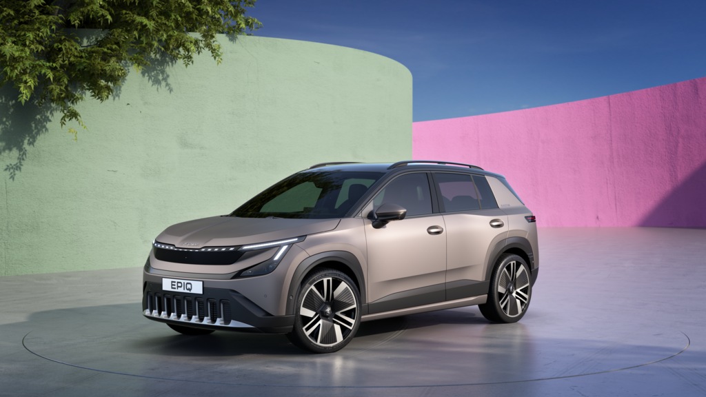 Škoda Epiq steht vor einer farbenfrohen Kulisse mit grünen und rosa Wänden. Der Wagen hat ein elegantes Design und glänzt unter dem blauen Himmel. Im Hintergrund gibt es auch einen Baum mit grünen Blättern.