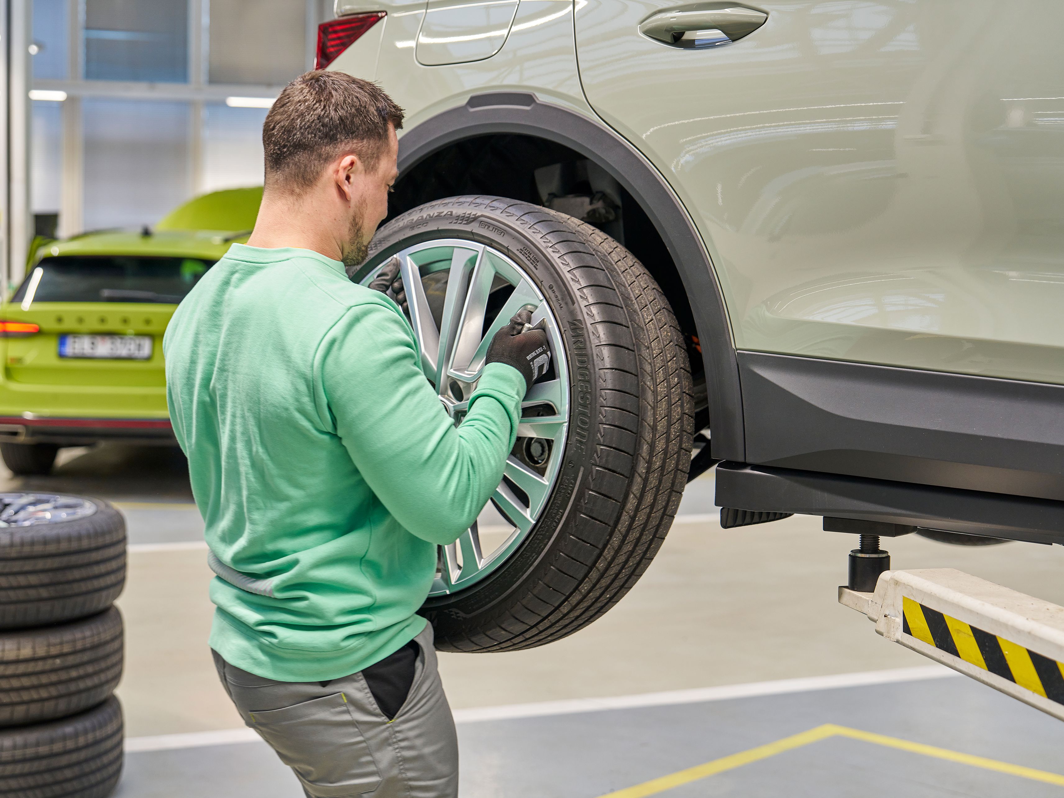 Ein Škoda Mechaniker in einer Werkstatt steckt ein neues Komplettrad an einem Škoda an.