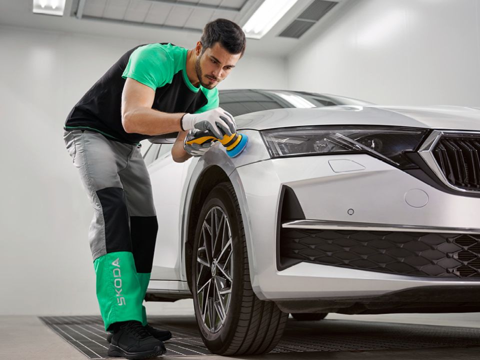 Ein Škoda Mechaniker poliert  den Lack bei einem silbernen Škoda.