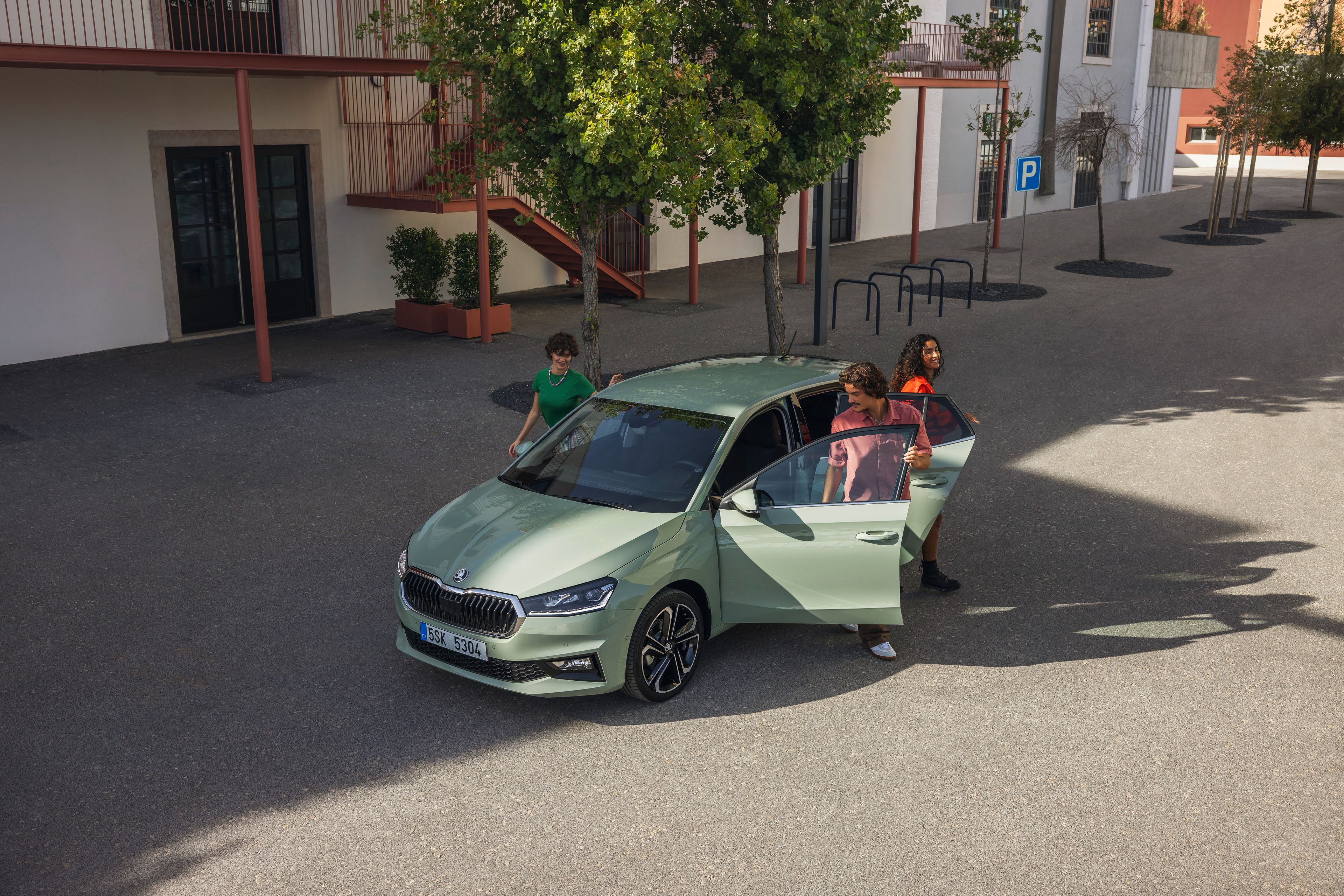 Drei Personen steigen aus einem grünen Škoda Fabia aus