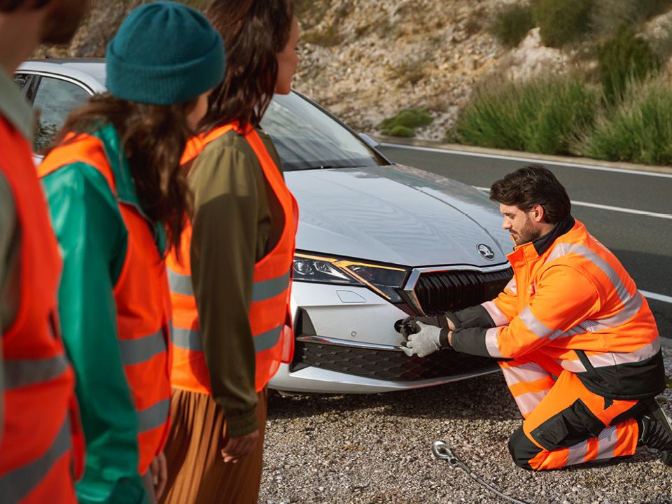 Eine Mann vom Abschleppservice befestigt ein Seil an einem Škoda.