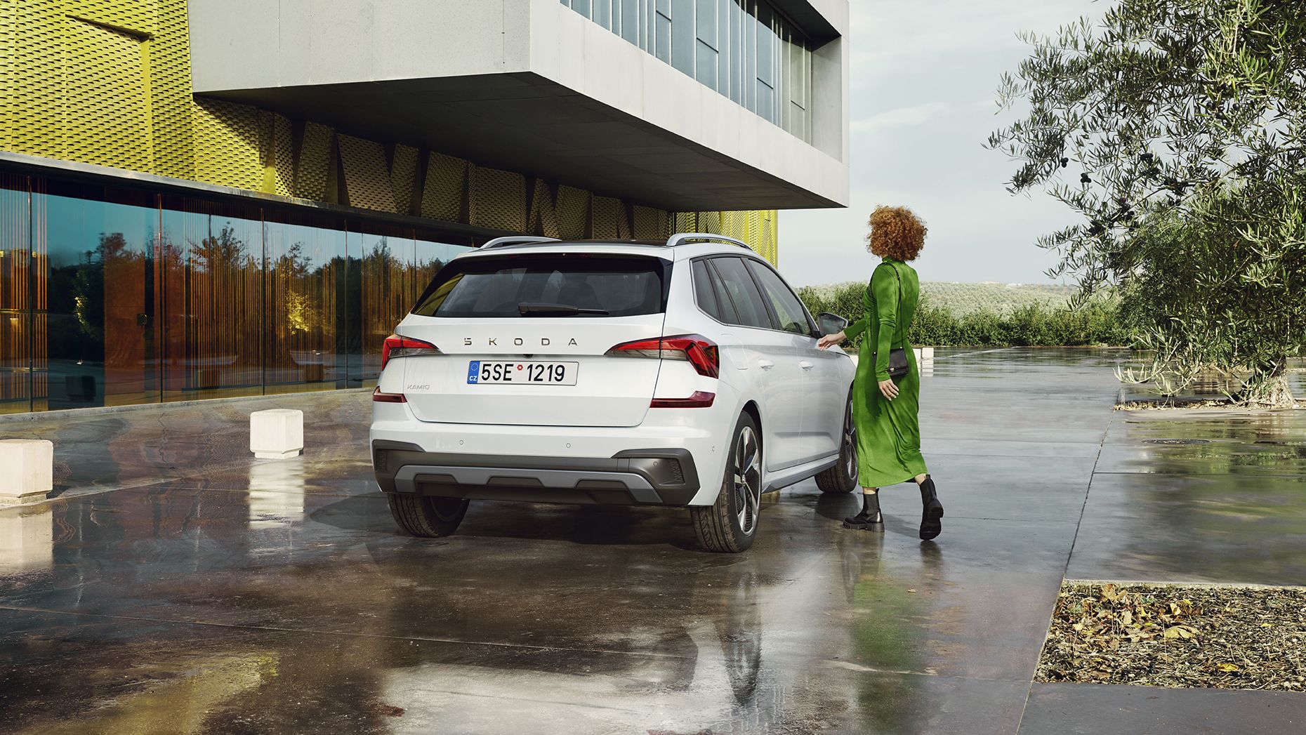 Eine Frau steht neben einem weißen Škoda Kamiq