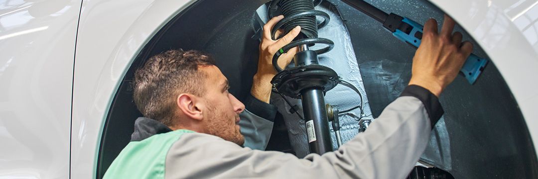 Ein Škoda  Mechaniker kontrolliert den Stoßdämpfer eines Škoda.