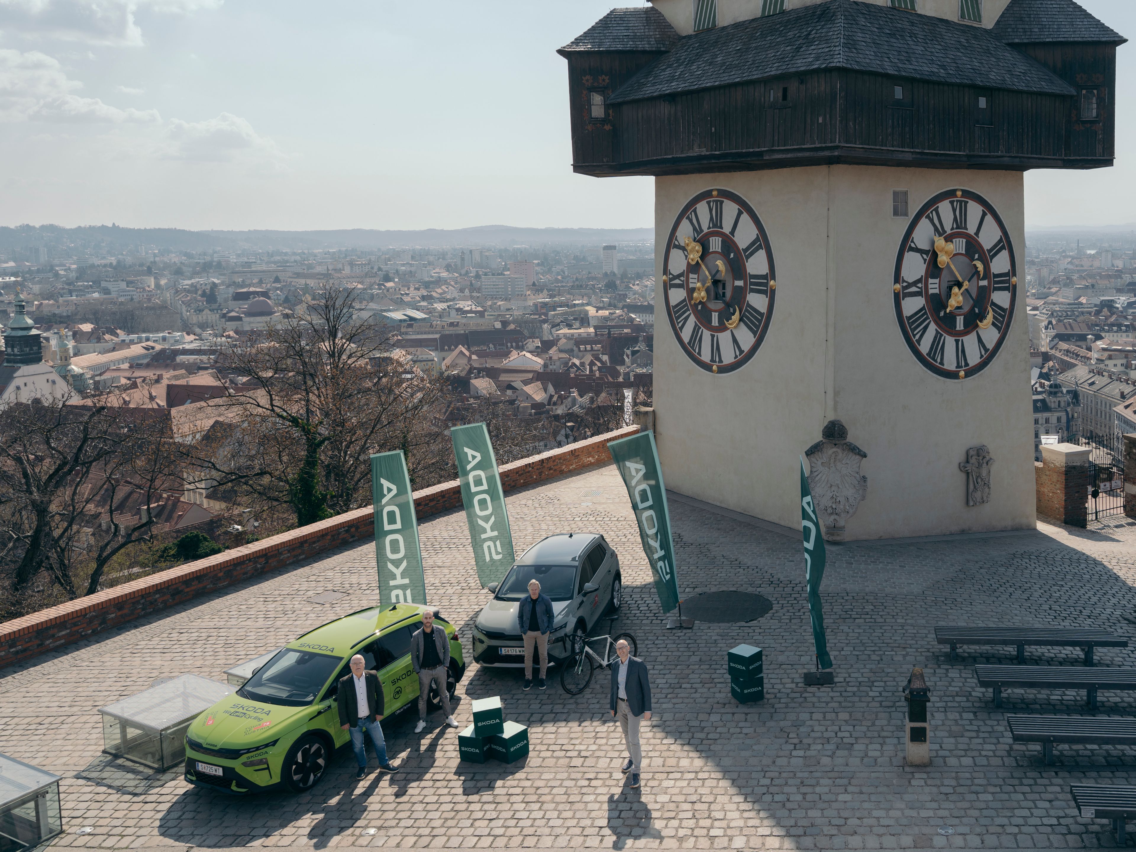 zwei Škoda Elroq vor Uhrturm in Graz mit Škoda Team und Tour of Austria Team