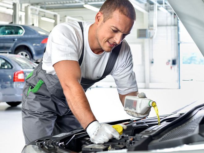 Ein Škoda Mechaniker füllt die Bremsflüssigkeit nach