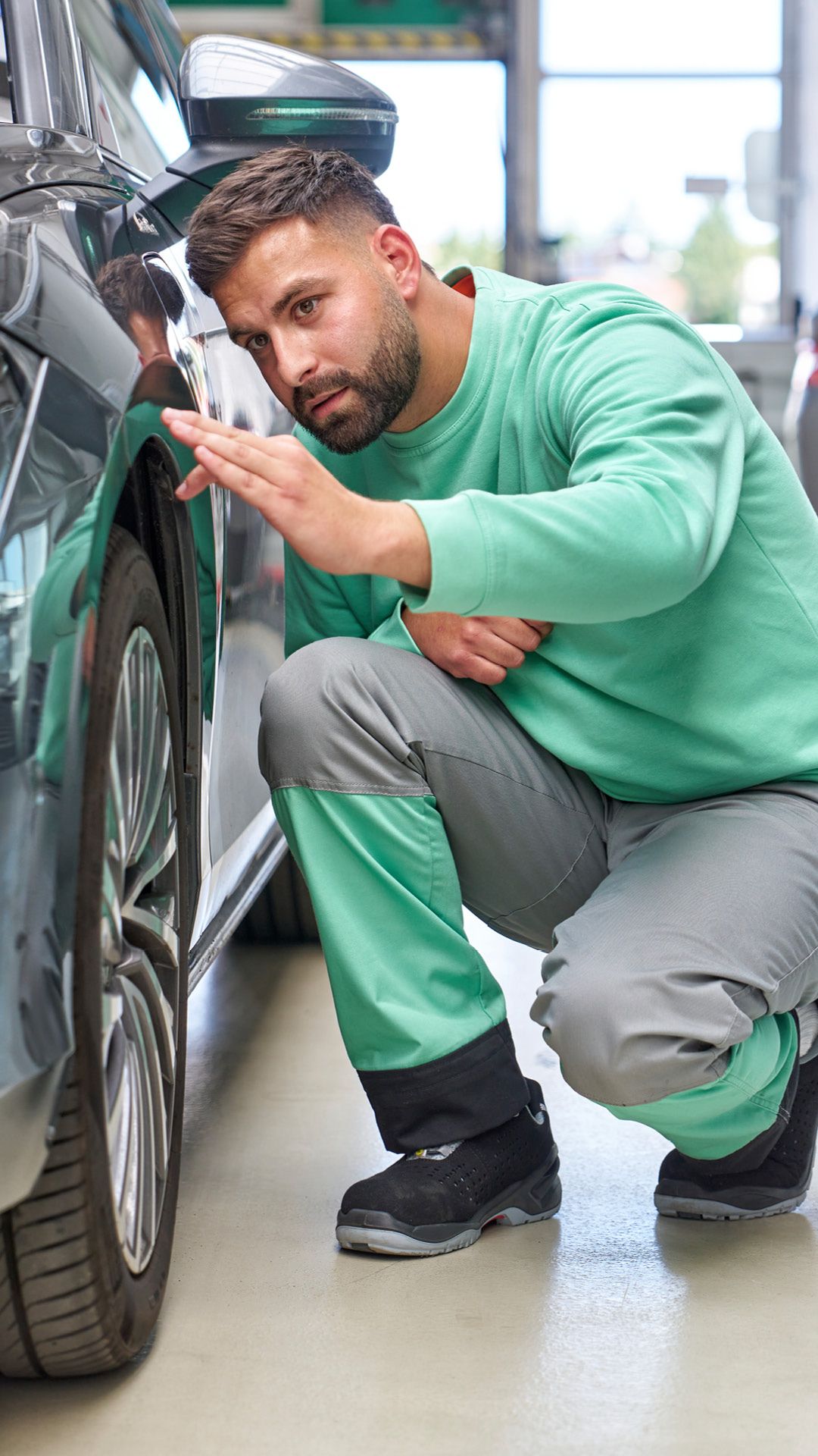 Ein Škoda Mechaniker kontrolliert den Lack bei einem grauen Škoda.
