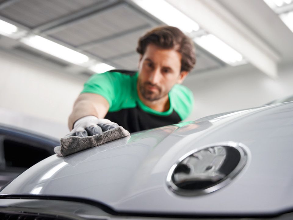 Ein Škoda Mechaniker poliert den Lack eines Škoda mit einem Tuch.
