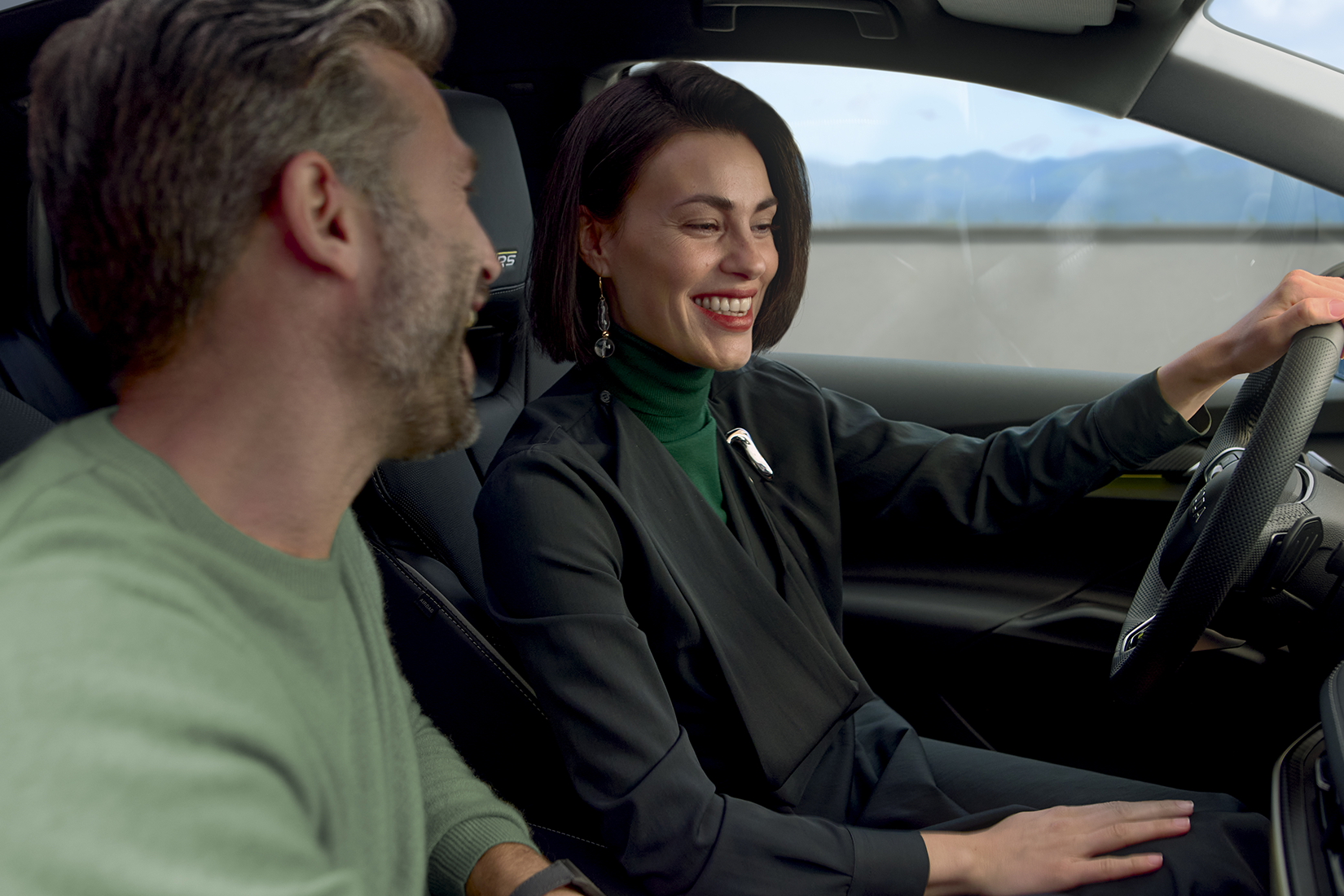 Zwei Personen sitzen im Auto und blicken auf das Infotainment