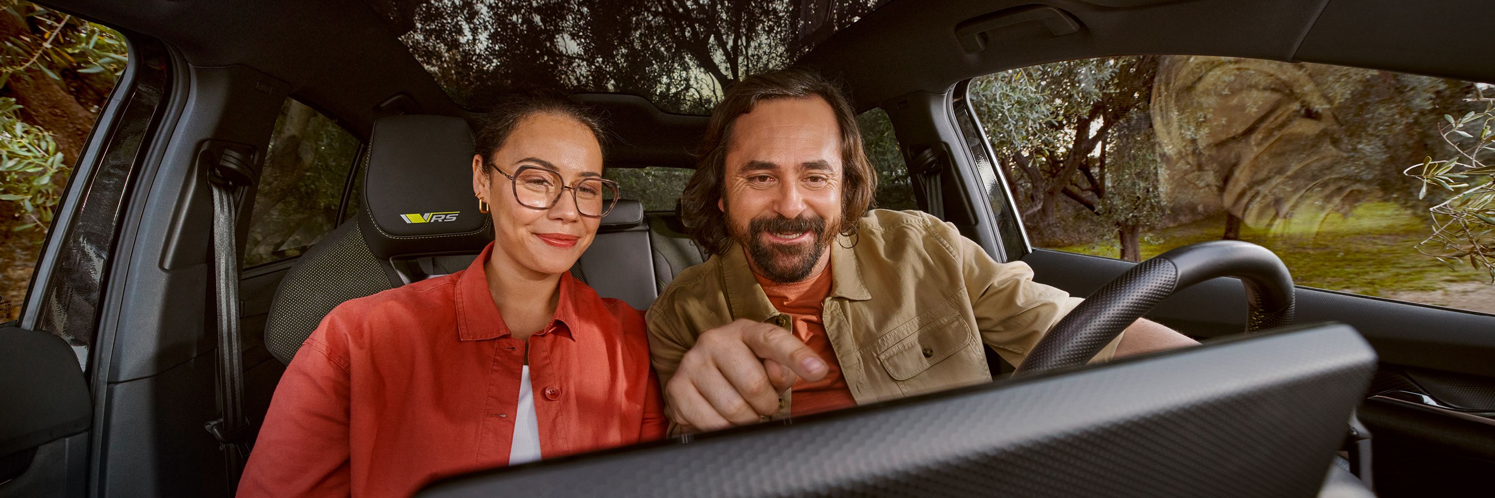 Ein Mann und eine Frau informieren sich am Infotainmentsystem im Cockpit eines Škoda