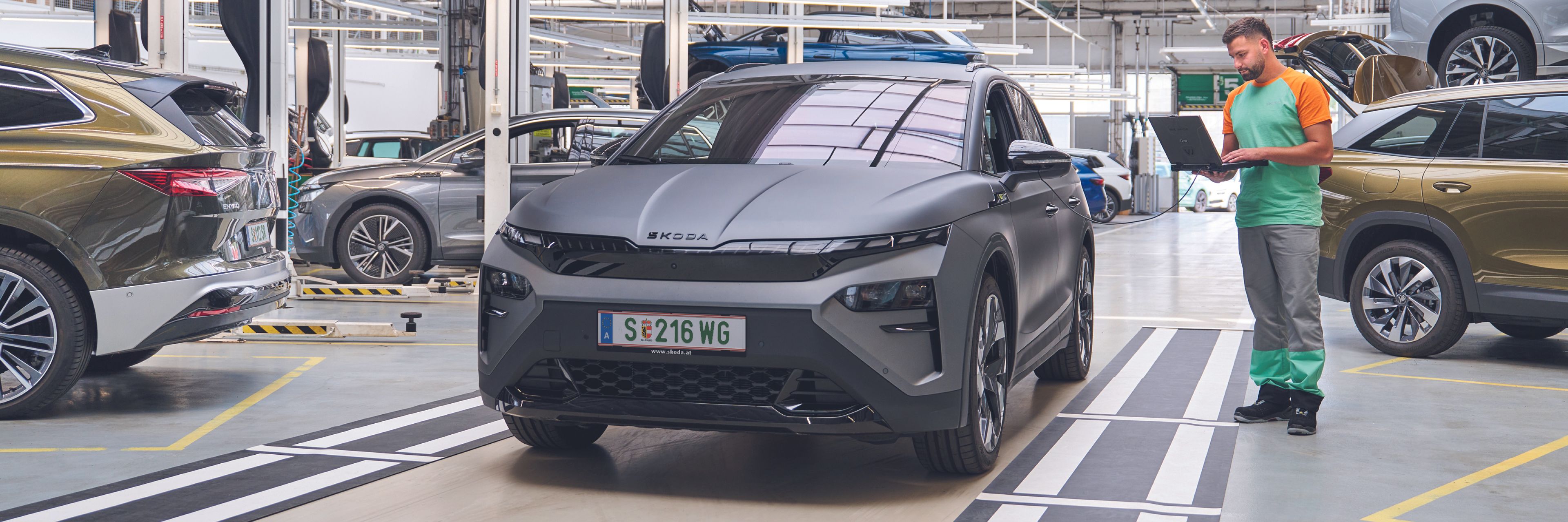 Ein Škoda Mechaniker kontrolliert mit seinem Laptop die Elektronik eines grauen Škoda.