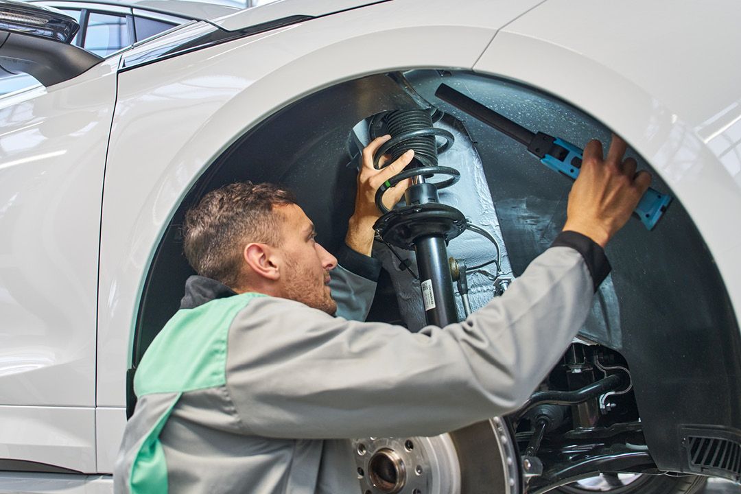 Ein Škoda  Mechaniker kontrolliert den Stoßdämpfer eines Škoda.