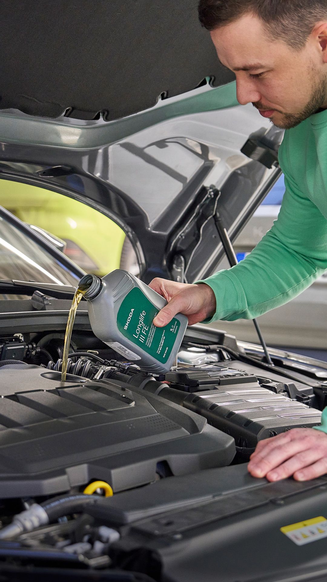 Ein Škoda Mechaniker beim Nachfüllen von Motoröl.
