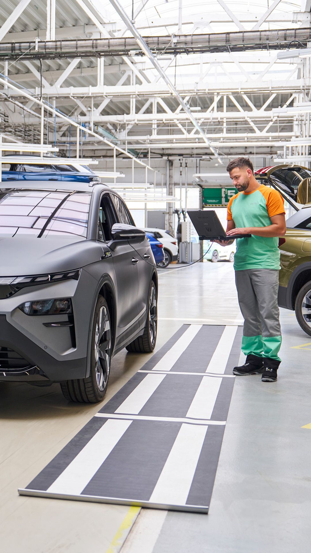 Ein Škoda Mechaniker kontrolliert mit seinem Laptop die Elektronik eines grauen Škoda.