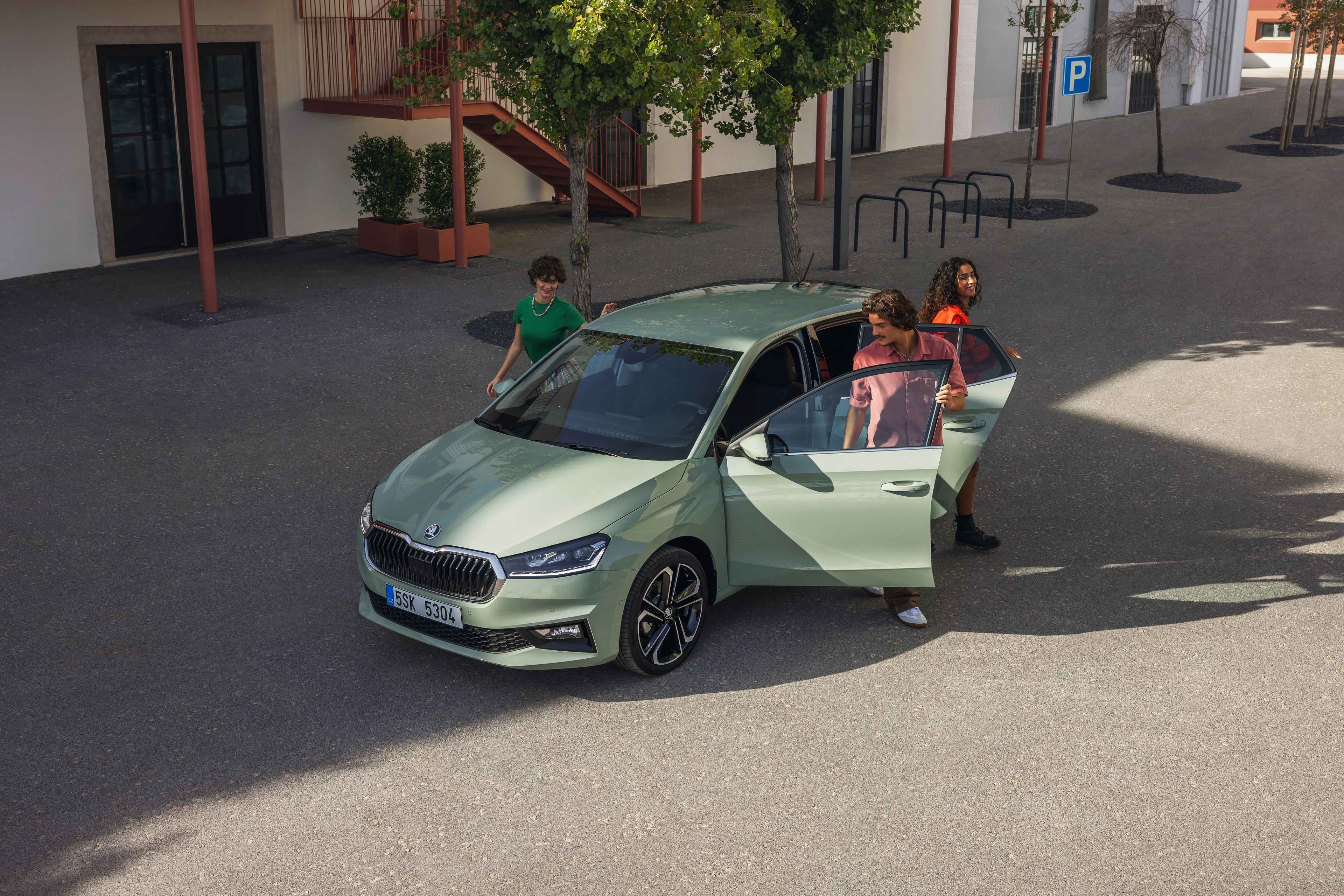 Drei Personen steigen aus einem grünen Škoda Fabia aus