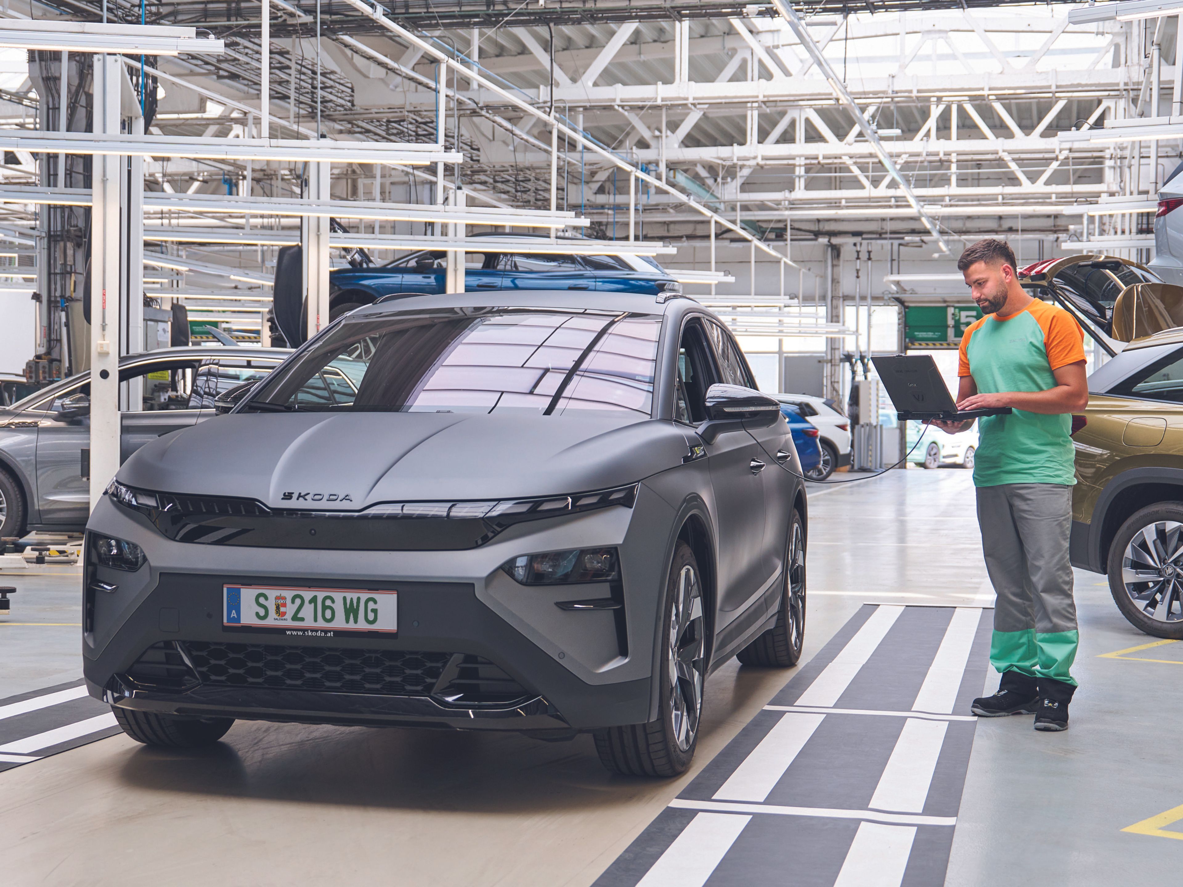 Ein Škoda Mechaniker kontrolliert mit seinem Laptop die Elektronik eines grauen Škoda.