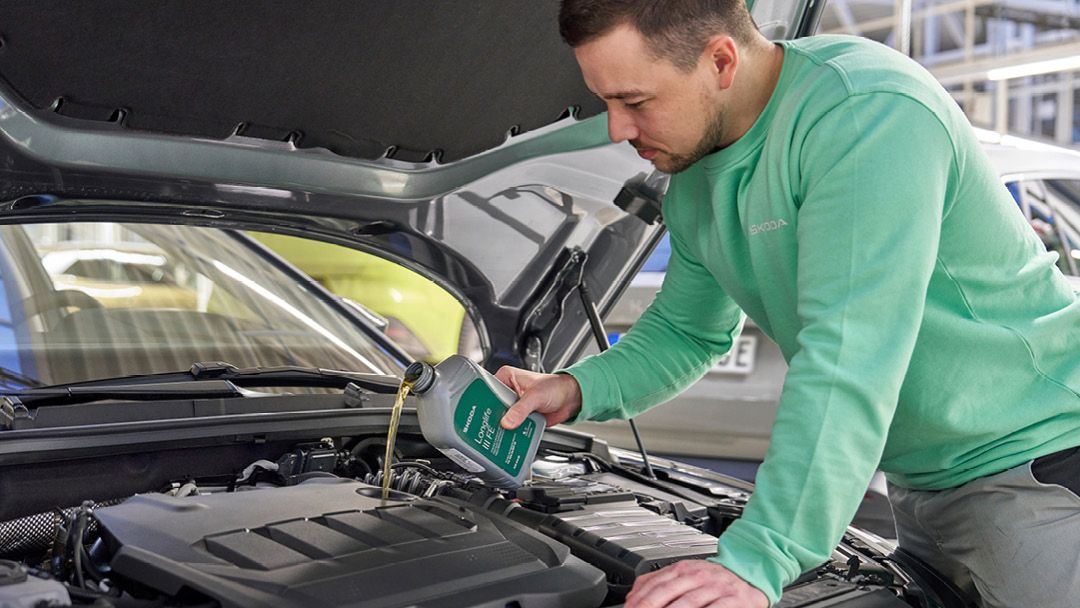 Ein Škoda Mechaniker beim Nachfüllen von Motoröl.