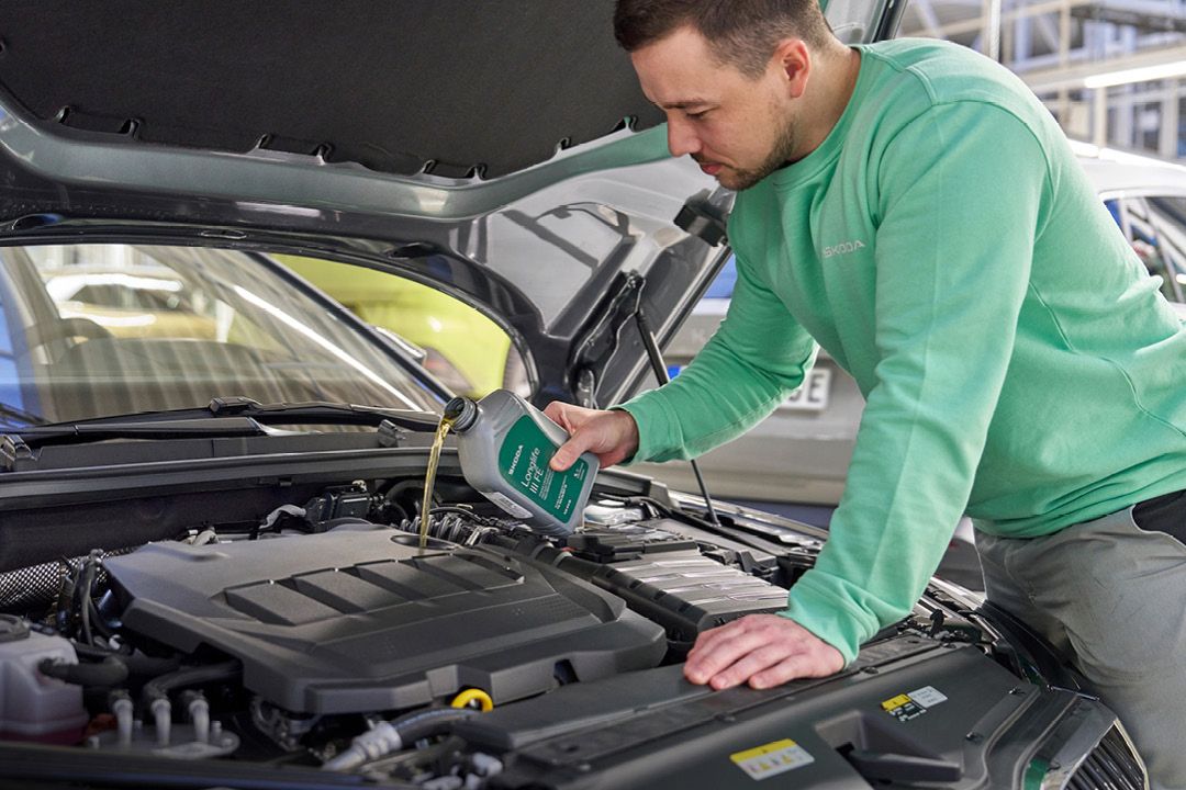 Ein Škoda Mechaniker beim Nachfüllen von Motoröl.