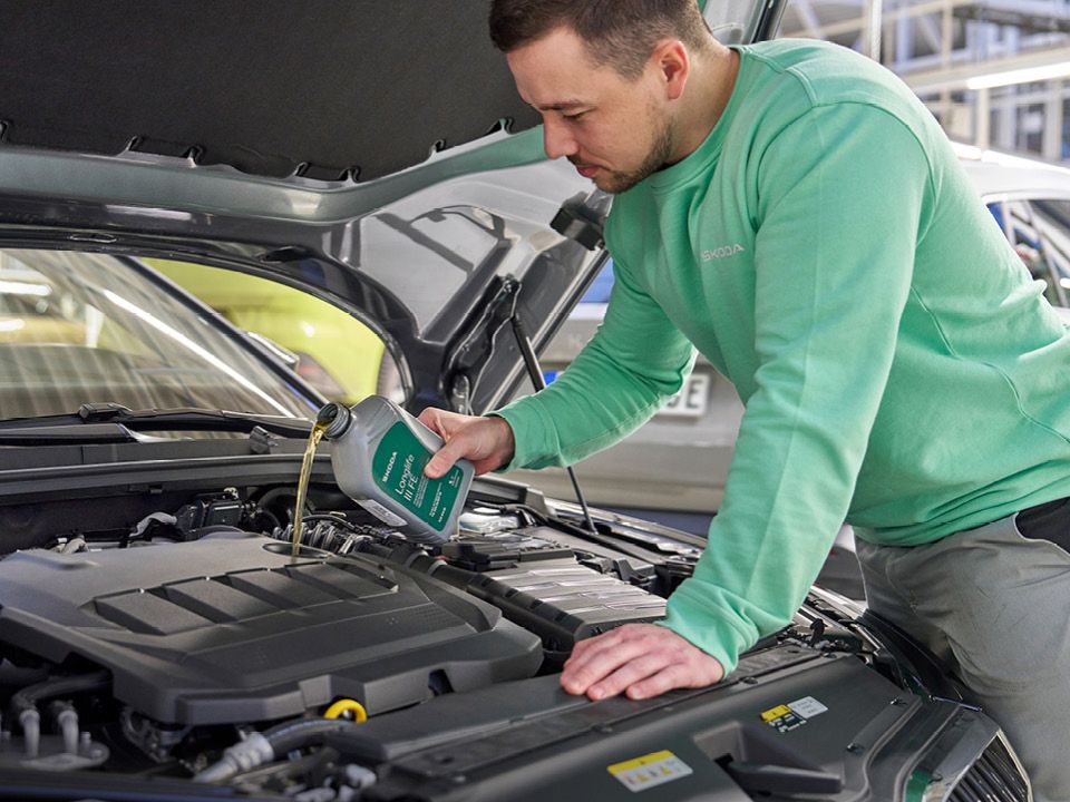 Ein Škoda Mechaniker beim Nachfüllen von Motoröl.