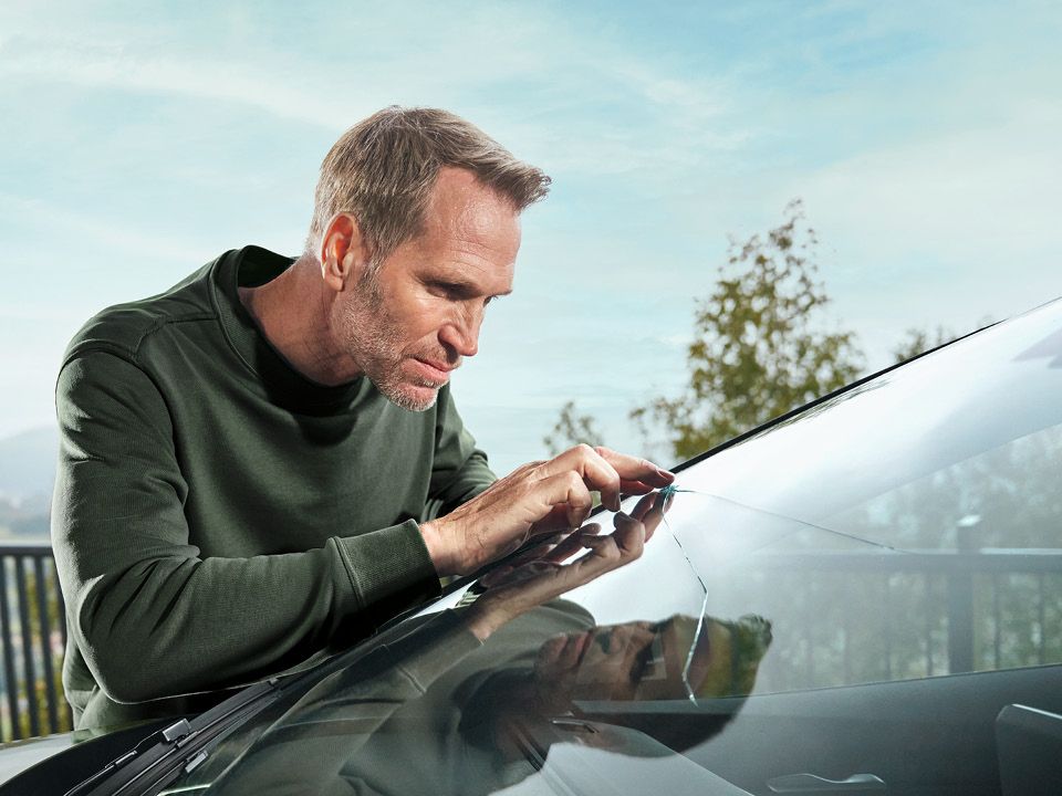 Ein Škoda Techniker kontrolliert einen Steinschlagschaden an einer Windschutzscheibe.